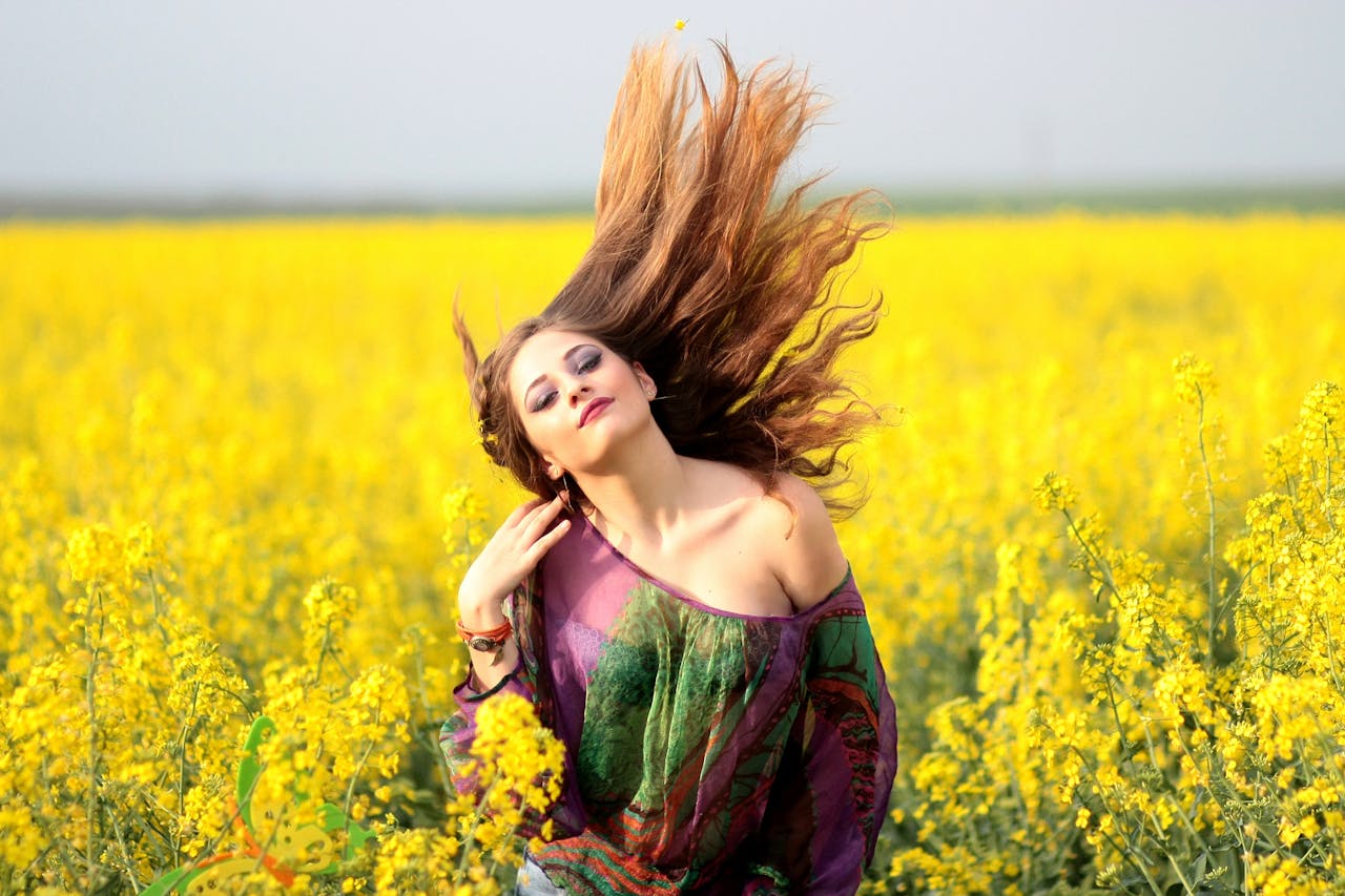 Vibrant portrait of a woman in a yellow flower field, exuding happiness and freedom.